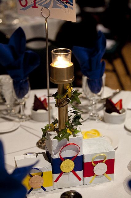 Olympic themed centerpieces Olympic Theme Table Decorations, Olympic Table Decorations, Olympic Centerpieces Table Decorations, Olympic Centerpieces, Olympic Cocktail, Golf Tournament Ideas Fundraising, Olympic Decorations, Vbs Olympics, Olympics Decorations