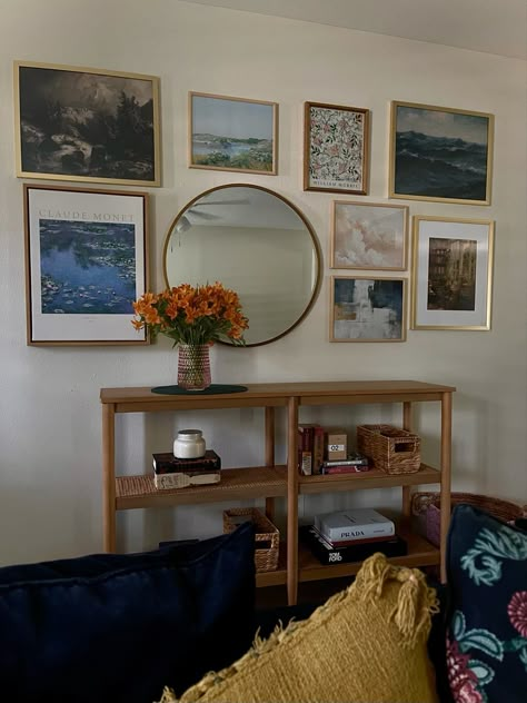 Entryway gallery wall including impressionist art prints and a gold mirror. A light wood console bookcase and lightly styled shelves with a few classic books, fashion books, and candles. Gallery Wall Console Table, Wall With Console Table, Gallery Wall Above Console Table, Circle Mirrors On Wall Living Room, Mirror And Picture Wall Layout, Gallery Wall With Mirror, Living Room Console Table Decor, Entry Way Gallery Wall, Mirror Gallery Wall Ideas