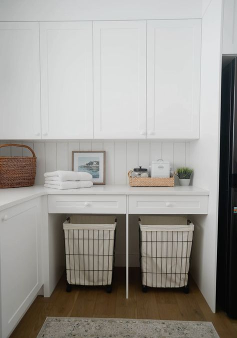 Laundry room, wood floors, rolling laundry hampers, stackable washer and dryer, area rug in laundry room, wood floors in laundryroom, artwork in laundry room, laundryroom decor, farmhouse sink Laundry Room With Laundry Basket Storage, Laundry Room Rolling Cart Storage, Laundry Room Built In Hamper, Built In Laundry Hamper, Big Laundry Room Ideas, Laundry Basket Cabinet, Stackable Washer Dryer Laundry Room, Laundry Room Ikea, Laundry Hamper Ideas