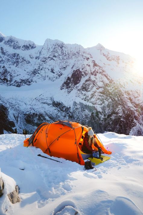 A woman camping outdoors during the winter. Her orange tent is set up on top of snow on a mountain. Linked to a Winter Camping and Hiking Guide. Winter Camping Gear, Wilderness Retreat, Hiking Places, Camping Inspiration, Camping Set Up, Mountain Camping, Best Camping Gear, Camping Aesthetic, Cold Weather Camping