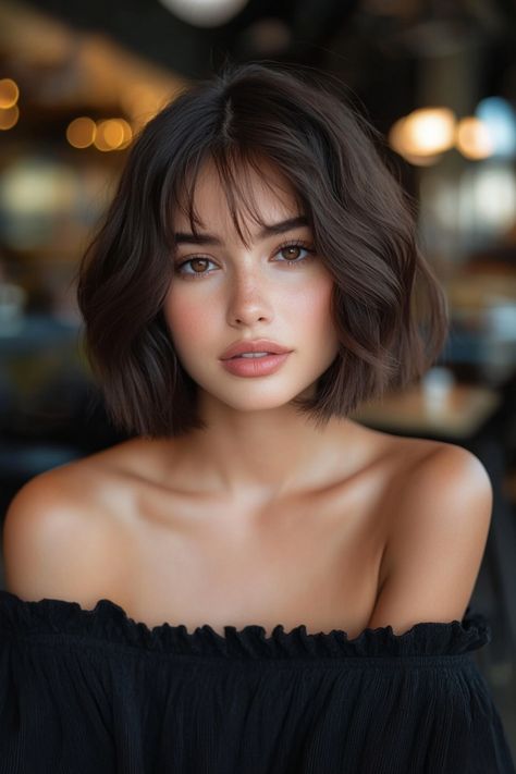 Woman with short dark wavy hair and off-shoulder black top, looking directly at the camera. Curtain Bangs On Bob, Bob Hairstyles Women, Textured Bobs, Straight Across Bangs, Highlighted Bangs, Sleek Bob, Hairstyles Women, Bob With Bangs, Bob Styles