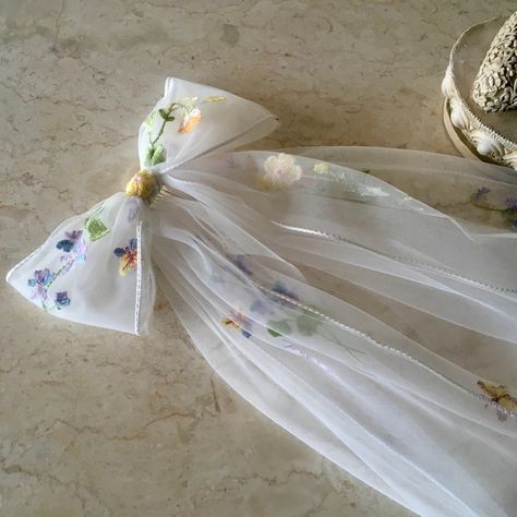 A beautifully embroidered, braid edged bow which has the option of being added to a gathered veil. The POSIE bow is created from beautiful flower embroidered off white tulle edged in braid. The bow has a second, longer layer of tails in plain off white, cut edge tulle.  There is an option to have the bow added to a gathered, cut edge veil also in plain off white tulle. ⚜️Bow in off white flower embroidered tulle, edged in braid ⚜️Bow: Width 20cm (8 inch)  Tails Length 60cm (24 inch) Plain Tulle Wedding Veil Bow, Wildflower Wedding Veil, Bow Veil Wedding, Amber Bedroom, Embroidered Wedding Veil, Veil Bow, Bow Veil, White Hair Bows, Tulle Bow