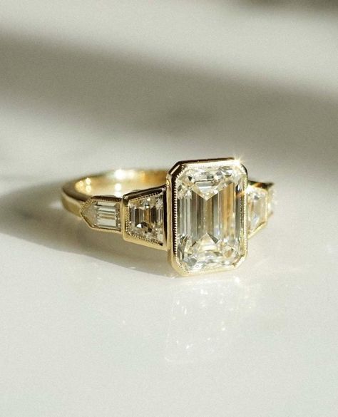 14K Gold Bezel Set Five Stone Ring, Emrald Cut Moissanite Engagement Ring, Anniversary Rings For Women, Promise ring, Low Profile Ring ✦ Centre Stone Details: ◈ Shape: Emerald  Cut Diamond ◈ Weight:  2.50 CT ◈ Diamond Size : 10*7 MM    ◈ Diamond: Moissanite  ◈ Color: Colorless ◈ Clarity: VVS ◈ Luster : Excellent ◈ Make: High Quality ✦ Side Stone Details: ◈ Shape: Baguette Tapped   Cut Diamond ◈ Weight: 6*3*2 MM  Each ( 1.00 CT Total ) ◈ Diamond: Moissanite  ◈ Color: Colorless ◈ Clarity: VVS ◈ Luster: Excellent ◈ Make: High Quality ✦ Side Stone Details: ◈ Shape: Bullate Cut Diamond ◈ Weight: 3*2 MM 0.25 CT Total  ◈ Diamond: Moissanite  ◈ Color: Colorless ◈ Clarity: VVS ◈ Luster: Excellent ◈ Make: High Quality ✦ Ring Details:- ◈ Metal: 18K/14K/ 10K Solid Gold / 925 Sterling silver (Nickle Fr Engagement Ring Cut, Pretty Engagement Rings, Bezel Set Engagement Ring, Dream Rings, Bezel Engagement Ring, Cute Engagement Rings, Art Deco Wedding Rings, Future Engagement Rings, Emerald Cut Engagement