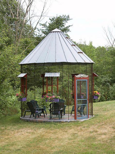 A classic farm structure gets reincarnated as a gazebo.  -- Placed at grade, pavers provide a pretty pattern underfoot.  -- Purple flower boxes at each "window" offer a sweet pop of color and foliage.  -- Charming details add character to a gazebo, such as the metal "shades" over the window and the winged sculpture over the door here.  -- a good gazebo requires minimal maintenance. Screened In Garden, Grain Bins, Crib Ideas, Corn Crib, Silo House, Backyard Gazebo, Outside Living, House Floor, Pole Barn