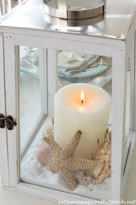 Beach Table Setting With Lighthouse Lantern Centerpiece | http://betweennapsontheporch.net/beach-themed-table-setting-tablescape-with-lighthouse-lantern-and-shell-sailboat-dishware/ Beach Table Settings, Beach Centerpieces, Beach Wedding Centerpieces, Beach Bridal Showers, Shells And Sand, Beach Table, Lantern Ideas, Smart Tiles, Lantern Centerpieces