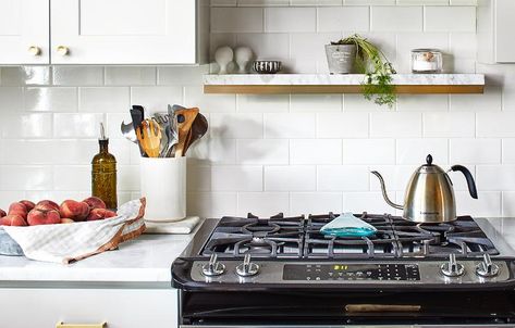 Marble and wood floating shelf designed above a gas stove atop white subway tiles in transitional kitchen design. Dark Blue Kitchen Cabinets, Stove Shelf, Montana Kitchen, Dark Blue Kitchens, Oven Shelf, White Wood Paneling, Grey Bathrooms Designs, Transitional Kitchen Design, Glen Arbor