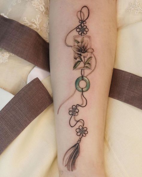 🌻 시온 on Instagram: “Black lily and black stringed norigae with jade ornament on her arm, done @studio.yasaeng” Japanese Charms Tattoo, Norigae Tattoo, Omamori Tattoo, Small Japanese Tattoo, Tatuaje Cover Up, Charm Tattoo, Body Tattoo Design, Korean Tattoos, Fan Tattoo