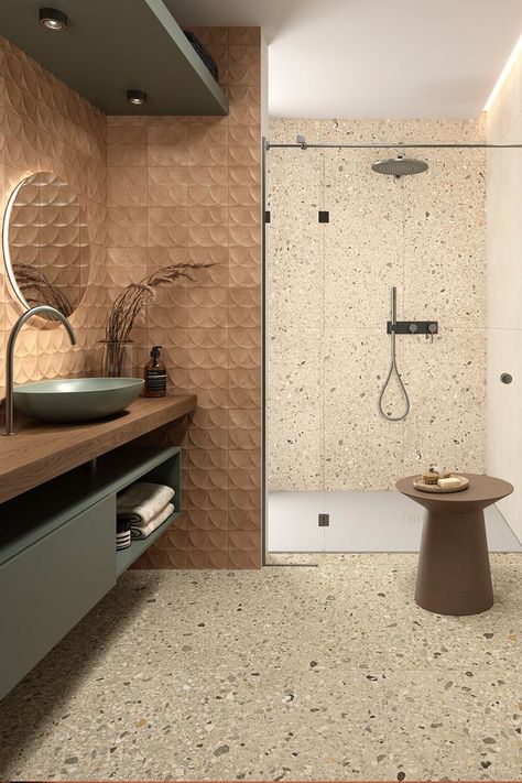 Rich in character and contrast, Arkistyle is a collection by Marca Corona that reinterprets Terrazzo tiles. Its Shade Warm variant flows beautifully both on the bathroom floor and the shower wall. Above the sink, Terracreta Forma Chamotte and its smooth embossment adorn the space with a soft caramel shade and complement the Multiforme Dune Tufo porcelain stoneware reflected on the mirror. Terrazo Tiles Bathroom, Terrazzo Tiles Bathroom, Bathroom Tiles Combination, Bathroom Inspiration Modern, Beige Tile, Unglazed Porcelain, Terrazzo Tiles, Italian Tiles, Tile Stores