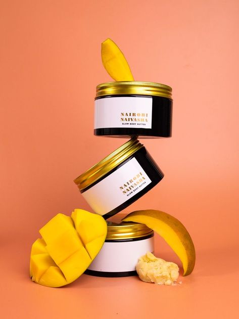 Three Nairobi Naivasha Glow Body Butter jars stacked on top of each other angled and levitating. Product photography styling is completed with raw mango pieces and raw shea butter. The whole composition is in orange and yellow colours. Body Cream Photography, Skincare Product Photography, Product Photography Styling, Soap Photography, Projector Photography, Levitation Photography, Mango Cream, Body Butters Recipe, Candles Photography