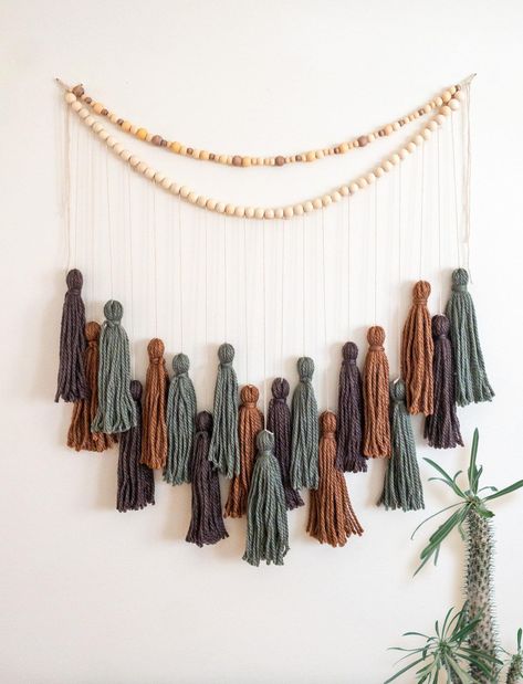 Yarn Tassel Garlands are a great way to incorporate texture and warmth into a space. Bring a bohemian flair to nurseries, living rooms, bedrooms, or party venues with a handmade Yarn Tassel Garland. Whether you're creating a cozy reading nook or sprucing up for a celebration, this garland is the perfect finishing touch. This item is made to order. Processing time is 1-3 days.  Measurements: Garland  Length: "34 laid flat, hung 30"  Depth - longest strung tassel is 33" Tassels Length: 10"  Like the garland but want a different color or length? I love custom orders! Hit the Custom Order button or send me a message of what you would like. Processing time for custom orders is 7 -10 business days. Shipping options: USPS Priority Mail (1-4 days) USPS First Class Mail (2-6 days) USPS Priority Mai Yarn Table Garland, Crochet Tassel Garland, Crochet Boho Garland, Diy Garlands, Yarn Garland, Crochet Garland With Beads, Fall Yarn Garland, Fall Yarn Tassel Garland, Yarn Banner Diy Tassel Garland