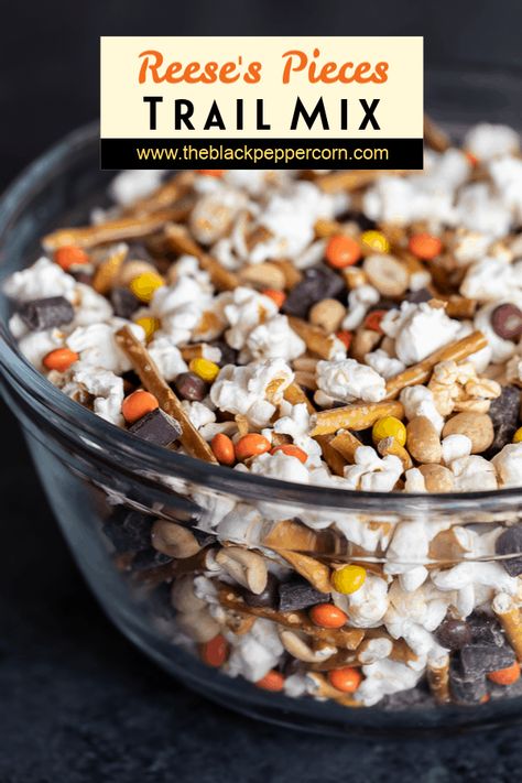 Reese's Pieces Trail Mix Recipe - Make a snack mix at home with mini Reese's Pieces, chunks of dark chocolate, peanuts, pretzel sticks and sweet and salty popcorn. Great for movie night, road trips or an after school snack! Popcorn Chex Mix Recipes, Popcorn Trail Mix, Popcorn Trail Mix Recipes, Trail Mix With Reeses Pieces, Movie Snacks At Home, Halloween Popcorn Mix Easy, Halloween Popcorn Trail Mix Recipe, Candy Corn Trail Mix Fall Snacks, S’mores Trail Mix Recipe Easy