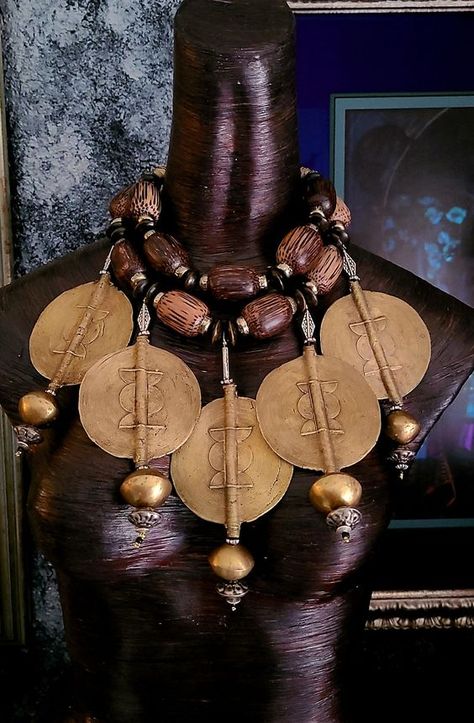 This stunning bespoke African tribal - ethnic oversized beaded chest piece is from my private vault and it is now available for purchase! Five oversized African lost wax brass Baule sun disks are featured in this piece. Each of these 3.5" jumbo size brass beads are currently retailing for $100.00 each!! A huge brass bicone is suspended from the end of each disk along with a brass rhinestone rondelle, various metal beads and a black seed bead. The necklace adjusts from 16-20" and closes with gold tone hardware, a fancy xl lobster claw clasp and a 4" extender chain. The necklace is comprised of huge wood beads, wood rondelles, brass spacers, African lost wax brass beads and ornate gold tone round beads. A lightweight and comfortable piece from the Atelier of Kat Kouture! Worldbuilding Clothes, Rocker Chic Accessories, Trill Art, African Inspired Decor, African Royalty, African Accessories, Unique Pendant Necklace, African Necklace, African Textiles