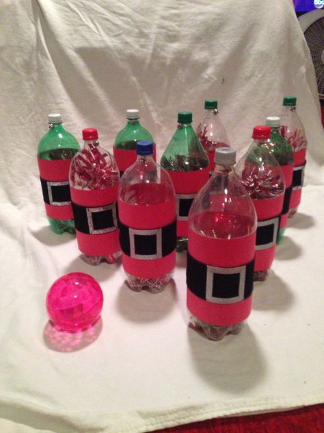 Santa Bowling Game! I made these from 2-liter bottles, paper, ribbon, & a Dollar Store small plastic ball. We used them for my boys school parties this year, & they were a HUGE hit!!! Side note: I put garland inside the bottle to give them a little bit of weight, so they weren't as easily knocked over. I think they turned out pretty cute! Christmas Bowling Game, Winterfest Games, Christmas Fayre Games, School Christmas Fair Ideas, Christmas Carnival Games, Diy Christmas Party Games, Preschool Christmas Party, Christmas Tree Game, Christmas Party Games For Kids