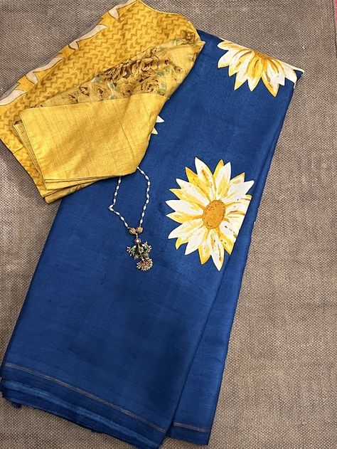 Mila indigo sunflower kanchi silk saree is a beautiful buttery feel kanchipuram silk saree with sunflower inspired prints on the body and a self tone blue indigo zari lined pallu and blouse piece. It can be paired with the yellow jwala tussar blouse as well. The saree may have some imperfections due to the process of handprinting and drying involved. But it only adds to the beauty of a handcrafted product. To view similar sarees, pls click on https://aavaranaa.com/product-tag/mila/ Blue Saree With Yellow Blouse, Normal Saree, Painting Sarees, Mangalagiri Sarees, Partywear Sarees, Saree Styling, Blouses Designs, Traditional Blouse Designs, Indian Saree Blouse