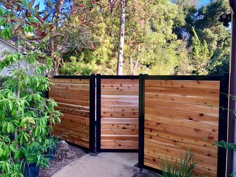 Beautiful 6' Fence with Cedar infill, clear coat stain to show the natural beauty of the wood! Visit Perimtec.com today to get your quote started! Steel And Wood Fence, Wood Fence With Metal Gate, Black And Cedar Fence, Horizontal Wood Fence With Metal Posts, Slip Fence Ideas, Horizontal Wood Fence Gate, Modern Wooden Fence, Wood And Metal Fence, Home Fence Ideas