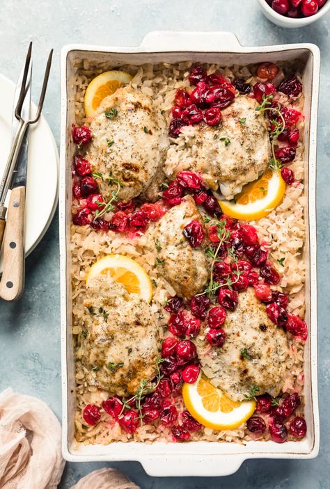 Overhead photo of Baked Orange Cranberry Chicken & Rice in a white casserole dish garnished with orange slices and fresh thyme with a ramekin of cranberries, neutral linen, stack of plates, knife and carving fork arranged around the dish. Cranberry Rice, Fresh Cranberry Recipes, Cranberry Baking, Orange Baking, Cranberry Chicken, Fluffy Rice, Baked Chicken Tenders, Orange Cranberry, Croutons Homemade