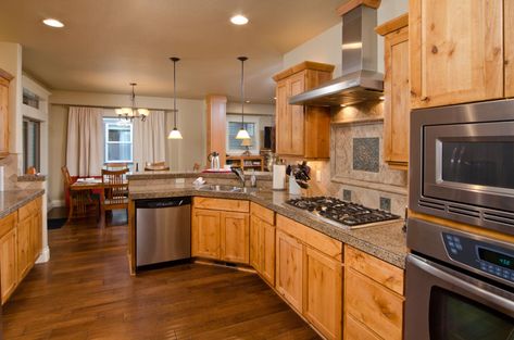 Kitchen with wood floor, oak cabinets, stove, hood, and recessed lights Honey Oak Cabinets With Brass Hardware, Hardwood Floors With Oak Cabinets, Vinyl Plank Flooring With Honey Oak Trim, Early American Stain On Oak Cabinets, Honey Oak Cabinets With Dark Wood Floors, Wood Floors With Honey Oak Cabinets, What Color Floor With Honey Oak Cabinets, Oak Cabinets With Dark Floors, Honey Oak Cabinet Kitchen Ideas