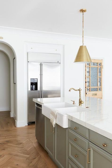 Gray-green kitchen island features a dual farmhouse sink with an antique brass vintage style hook and spout faucet under gold lights. White Beveled Subway Tile, Kitchen Dining Nook, Green Kitchen Island, Vintage Pantry, Pure Salt Interiors, White Shaker Kitchen, Green Island, Pure Salt, Newport Coast