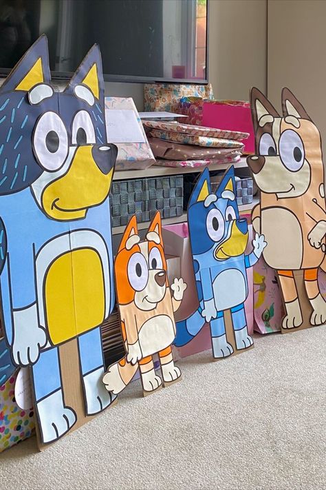 Four large Bluey character boards, setup in a lounge with presents behind. Diy Bluey Centerpieces, Bluey Cardboard Cutout, Bluey Cut Outs, Diy Bluey Pinata, Diy Bluey Cutouts, Bluey Birthday Centerpieces Diy, Bluey Classroom Decoration, Diy Bluey Decorations, Bluey Classroom Themes