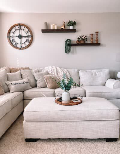 Cream sectional sofa adorned with wood floating shelves and natural decor accents. Neutral living room decor inspiration includes extra large wall clock, wood and metal tray and faux eucalyptus centerpiece. Cream throw pillows, cream leopard throw blanket and more adorn my large cream couch in my coastal decor style lounge space. Source list included. #creamsectional #creamcouch #neutraldecor #coastalstyle #fauxgreenery #fauxeucalyptus #woodmetal #industrialdecor #throwpillows #throwblanket Shelves Over Couch, Loft Living Room Decor, Coastal Style Decor, Couch Wall Decor, Loft Living Room, Photowall Ideas, Sofa Wall Decor, Floating Shelves Living Room, Living Room Decor Neutral