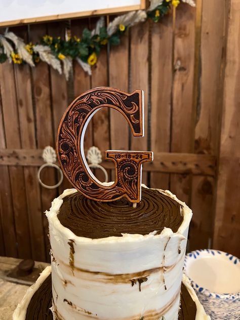 Add a touch of personalized charm to your special day with our Custom Ordered Leather Wedding Initial Cake Topper. Hand carved from quality leather, this topper features your initial on a 5-inch tall wooden letter. A unique and stylish addition to your wedding cake! Included are 2 wooden skewers that will slide into the bottom of the letter and easily slide down into your cake making it easy to insert and remove. This makes it super easy to display your new last name in your home after your spec Rustic Cake Toppers Wedding Country, Grooms Cake Outdoorsman, Wedding Cakes Topper, Western Wedding Isles, April Western Wedding, Leather Cake Topper, Mountain Western Wedding, Unity Branding Ceremony, Leather And Lace Wedding Theme