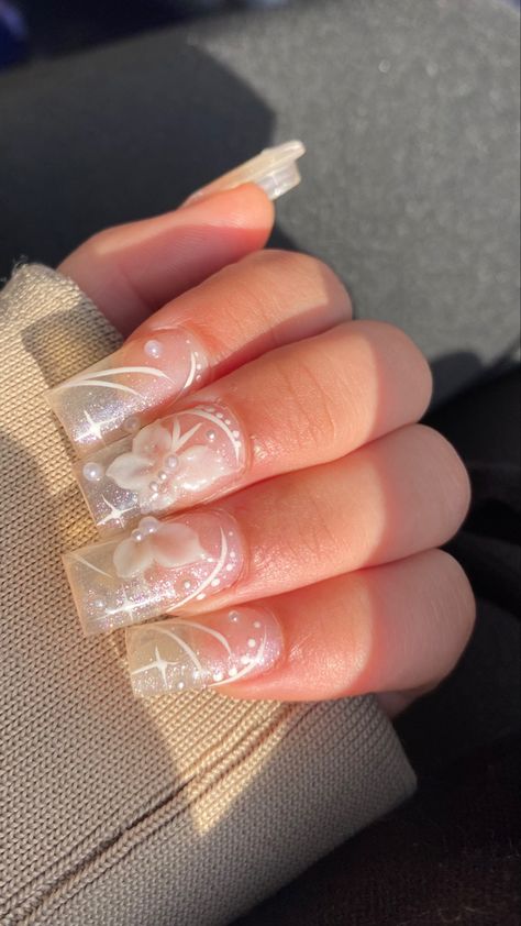 Photo of acrylics, most of the hand is covered by pulled-up beige hoodie sleeves, the fingers are bent over the sleeve to show the nails. The acrylics are translucent with very small glitter particles, drawn on the nails are stars and curved lines with dots, everything is drawn in white. The main feature of the nail are the 3D white butterflies white small faux pearls to represent the body and what looks like a thick acrylic to represent the wings, there are also small pearls in the background. 3d Acrylic Butterfly Nail Art, 3d Nail Butterfly, Clear Butterfly Nails, 3d Butterfly Nails, Butterflies Nails Acrylics, Nails Hacks, Ballerina Nails Short, Rounded Acrylic Nails, 3d Acrylic Nails