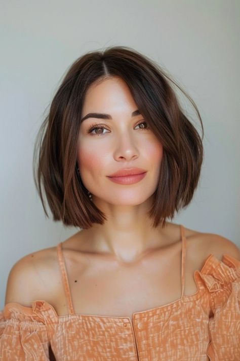 Woman with a short, brown bob haircut wearing a peach-colored off-shoulder top. Bob Thick Hair Round Face, Long Bob Hairstyles For Round Face, French Bob With Bangs Fine Hair, French Long Bob, Textured Bob With Curtain Bangs, French Bob Haircut Round Face, Edgy Short Bob, French Bob Thick Hair, Short Bob Round Face