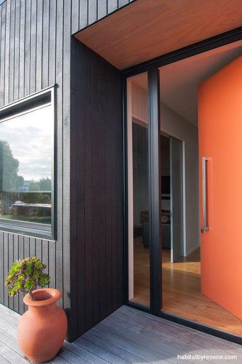 house exterior, black house, orange front door, black exterior, orange and black, black cladding Orange Front Door, Front Door Black, Black Cladding, Orange Front Doors, Metal Doors Exterior, Rustic Front Door, Mid Century Modern Exterior, Orange Door, Black Shutters