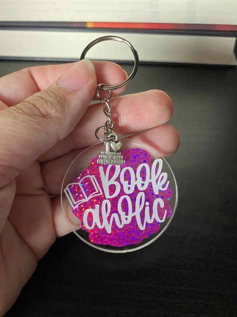 Do you love to read? Would you call yourself a bookaholic? Let the world know it with a cute keychain perfect for readers and other bookish types! These round acrylic keychains are 2 inches around. They're made with a pink holographic permanent vinyl with white permanent vinyl that says: Bookaholic. Some have a book graphic with a heart and some have one without a heart. All Bookholic keychains come with a special charm. Choose the one you want! Charms to choose from: - I Love to Read charm - On Holographic Keychain, Acrylic Round Keychain, Acrylic Round Keychain Ideas, Round Keychain Idea, Diy Acrylic Keychain Ideas, Circle Keychain Ideas, Acrylic Keychain Ideas Vinyl, Acrylic Keychains Diy Cricut, Vinyl Keychain Ideas