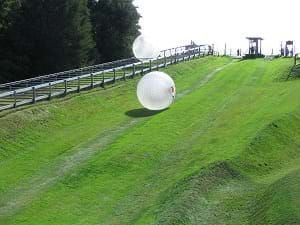 Zorbing, which shows a large ball rolling down a hill. Adventure Activities, A Hill, Cultural Experience, Travel Bugs, Beautiful Places To Visit, The Ranch, New People, Most Beautiful Places, Where To Go