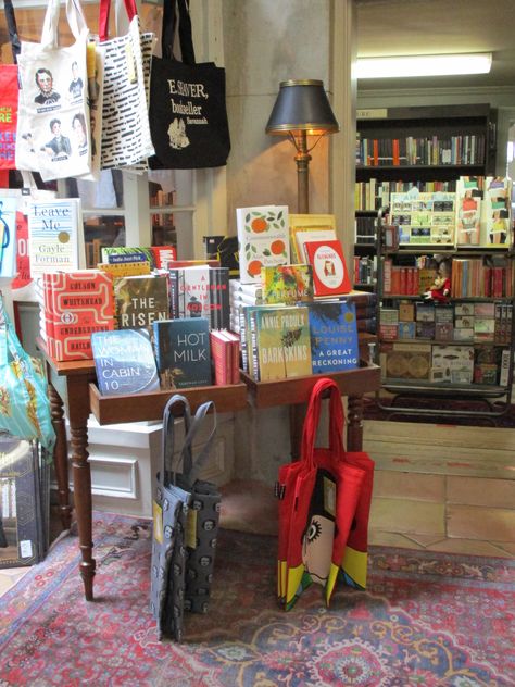 This little table display at E. Shaver Booksellers is in a key location between rooms. This repurposed desk makes a quaint statement, especially with the lamp, literary totes, and display of the week's newest book releases. Book Display Ideas Retail, Book Shop Display Ideas, Book Display Store, Book Shop Interior Design, Small Book Store Ideas, Book Store Display Ideas, Book Display Table, Book Store Design Interior, Book Store Display