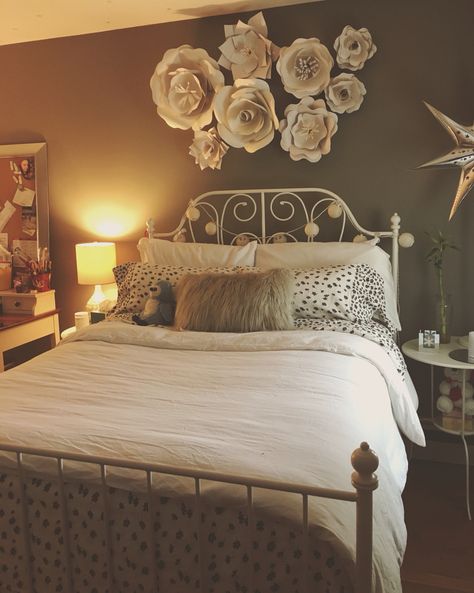 Metal bed and paper flowers Flowers On Bedroom Wall, Flower Wall Headboard, Flowers On Headboard, Flowers Above Bed, Fake Flower Headboard, Floral Bed Headboard, Dried Flowers Above Bed, Bedroom Wall Decor Ideas Above Bed, 20s Apartment