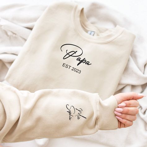 Introducing our Personalize Papa Embroidered Sweatshirt, the perfect gift for any proud grandpa or abuelo! This cozy sweater features a special touch - the names of your precious kids embroidered lovingly on the sleeve. With its soft and warm fabric, this sweatshirt is not only a stylish addition to any wardrobe, but also a sentimental keepsake that showcases the special bond between a grandpa and his grandchildren. It's the ideal Father's Day gift or a heartfelt surprise for a new grandpa. Give the gift of comfort and meaning with our personalized sweatshirt that celebrates the joy of being a grandpa! HIGH QUALITY MATERIALS: We selected comfortable, soft materials to ensure you stay warm and comfortable during the cold seasons. Diverse Colors: You can choose from a variety of colors accor Diy Father's Day Crafts, Warm Fabric, Father's Day Diy, Kids Names, Fathers Day Crafts, Embroidered Sweater, Embroidered Sweatshirt, Grandpa Gifts, Cozy Sweater