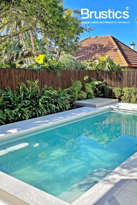 Smoked bamboo privacy fencing surrounding a tranquil swimming pool Bamboo Pool Landscaping, Wood Fences Around Pools Ideas, Bamboo Around Pool, Pool With Wooden Fence, Bamboo By Pool, Timber Pool Fence, Bamboo Fencing Around Pool, Mediterranean House Designs, Bamboo Landscape