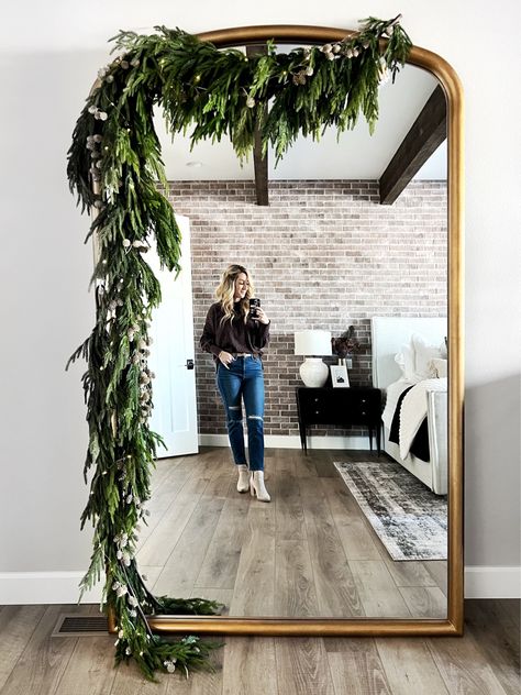 Floor Mirror With Garland, Foliage Around Mirror, Arched Mirror Christmas Decor, Christmas Wreath Mirror Ideas, Anthro Mirror Christmas, Garland On Floor Mirror, Garland Mirror Decor, Floor Mirror Christmas Decor, Arch Mirror Christmas Decor