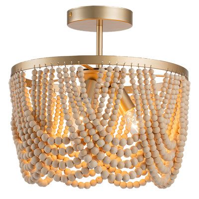 Drawing inspiration from the timeless Bohemian style, our Bohemian chandelier features oak wood beads and high-quality gold metal brackets. The layered wooden beads create captivating plays of light and shadow on the ceiling, infusing your space with a relaxed and romantic Bohemian ambiance. Finish: Gold | Bungalow Rose Pragati 3-Light Boho Wood Beaded Semi Flush Mount Wood / Metal in Yellow | 12.6 H x 12.6 W x 12.6 D in | Wayfair Beaded Light Fixture, Wood Beaded Chandelier, Boho Light Fixture, Bohemian Chandelier, Boho Lighting, Boho Chandelier, Wood Bead Chandelier, Gold Bedroom, White Chandelier