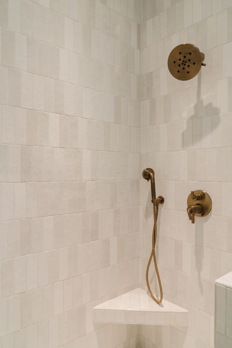 50/50 offset vertically stacked white shower tile with corner shower bench and antique brass fixtures. #thedendesigngroup #bathroomshower #bathroomtile #bathroomdesign #designinspo #showerdesign #luxegoldplumbing #luxurybathroomdesign #bayareainteriordesign Corner Shower Ledge, Corner Shower Bench Built In, Tiled Corner Shower Ideas, Vertical Rectangle Shower Tile, Corner Shower Tile Ideas, Shower With Corner Seat, Shower With Corner Bench, Shower Corner Bench, Shower Bench Built In