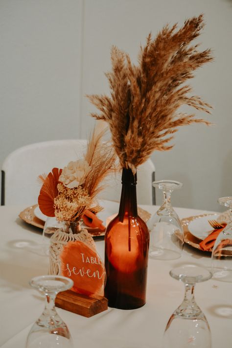 Amber Flower Vases Wedding, Autumn Boho Wedding Decorations, Amber Jar Centerpiece, Fall Floral Arrangements Wedding Centerpieces, Minimalist Fall Wedding Centerpieces, Burnt Orange Wedding Centrepiece, Wedding Reception Table Set Up, Burnt Orange Centerpieces Wedding, Amber Vases Wedding Centerpieces