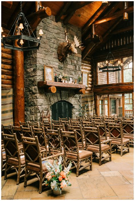 Rustic indoor ceremony setup at Whiteface Lodge, featuring rows of wooden chairs facing a grand stone fireplace adorned with a moose mount, cozy decor, and vibrant floral arrangements that complement the lodge’s natural charm. Adirondack Wedding, Adirondacks Wedding, Romantic Summer Wedding, The Adirondacks, Romantic Summer, Summer Celebration, Lake Placid, Mountain Views, Rustic Elegance