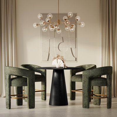 Our 5-piece dining set is a step above the rest with its space-conscious design and inviting mixed-materials look. It includes a round table and four armchairs fully wrapped in plush jacquard fabric. The table is crafted from solid and engineered wood with a black finish, and the circular table top rests on a classic pedestal base for a dynamic mod vibe we love. Measuring 45" wide, the table can easily accommodate up to four people. Chair Color: Forest Green | Orren Ellis Tiarah - Person Counter Cocktail High Table, Green Marble Dining Room Table, Modern Kitchen Table And Chairs, Round Dining Table Ideas, Counter High Dining Table Black, Green Velvet Dining Chairs Round Table, Olive Green Velvet Dining Chairs, Round Counter Height Table, 60" Round Modern Dining Table