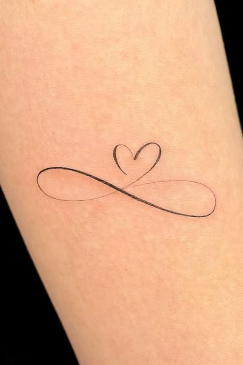 Infinity Heart1 Minimalist infinity heart tattoo on skin, symbolizing eternal love and connection. | Sky Rye Design Heart Tattoo On Heart, Small Infinity Wrist Tattoos For Women, Elegant Heart Tattoos, Red Infinity Tattoo, Forever Love Tattoo Symbols, Single Line Heart Tattoo, Heart Dates Tattoo, Infinity And Heart Tattoo, Colored Heart Tattoo