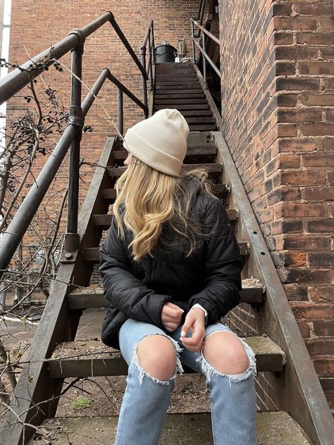 woman sitting on outdoor staircase, head turned the opposite way of the camera, wearing carhartt hat, black puffer jacket, and jeans Brown Beanie Outfit Winter, Cathartic Beanie Outfit, Carhartt Beanie Outfits, Cream Beanie Outfit, Black Beanie Outfit Aesthetic, Binnie Hat Outfits, Bennies Hats Outfits, Beige Beanie Outfit, Cute Beanies Outfits