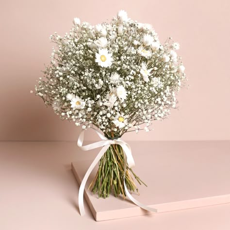 An elegant wedding bouquet plucked right out of the English countryside. Transport your special day to the blissful outdoors with our glorious Dorothy dried flower range. Specially crafted for weddings, each collection has something to suit your ensemble. With natural gypsophila and rodanthe daisies arranged by our in-house team, each bouquet is finished with a white ribbon for comfortable holding.This bouquet has been specially designed to stand upright, for all those moments during your celebrations when you're unable to carry it. This also makes it ideal for displaying in your home after your wedding - simply pop it pride of place and remember the joy of your special day every time it catches your eye.Dried flowers will last a long time, but if you look after them correctly, they will l Daisy Bridal Bouquet, Daisy Bouquet Wedding, Wedding Flowers Gypsophila, Flower Bridesmaid, Gypsophila Wedding, Elegant Wedding Bouquets, Bridal Wedding Bouquet, White Flower Bouquet, White Floral Arrangements