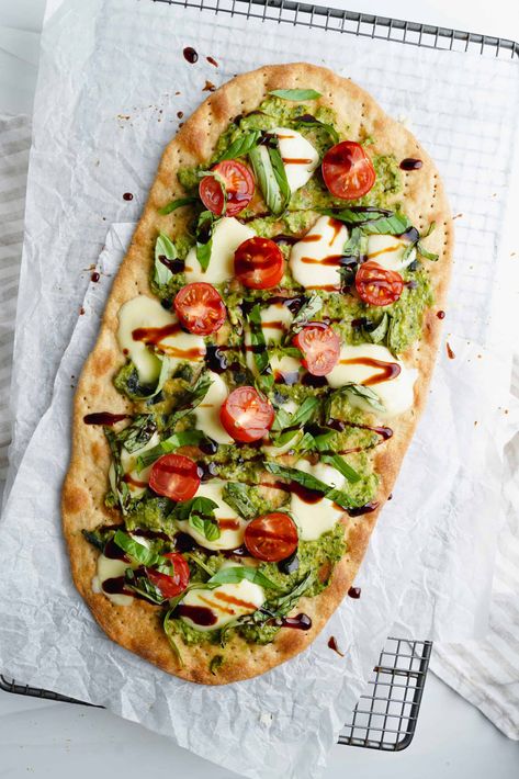 A savory dish inspired by the Italian Caprese salad, this flatbread is topped off with melted mozzarella, juicy cherry tomatoes, and tangy pesto sauce. Caprese Roll Ups, Italian Wraps Recipes, Flatbread Meals, Quick And Easy Flatbread Recipe, Flat Bread Wraps, Caprese Flatbread, Italian Caprese, Italian Caprese Salad, Caprese Appetizer