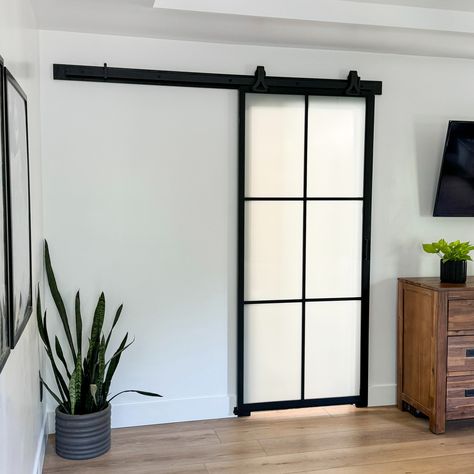 A 6-lite black metal barn door with frosted glass in a room with wood floors and white walls Bathroom Barn Door Ideas Master Bath, Bathroom Barn Door Ideas, Masonite Doors, Bathroom Barn Door, Modern Barn Door, Barn Door Kit, Black Front Doors, Door Kits, Transitional Living Rooms