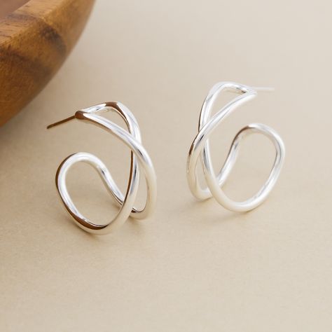 Forged by hand in solid sterling silver, the Crossover Hoop Earrings are a modern twist on classic hoops. One continuous piece of silver is hammered around stakes and soldered closed to form an endless loop, highlighting the woven crossover design at the front of the hoop. These earrings are made-to-order by hand in our bespoke metalsmithing studio in Stockport, New York. Instead of casting multiples of our designs, we fabricate each element by hand the old-school way using torches, hammers, and Handmade Sterling Silver Earrings, Architectural Earrings, Modern Silver Earrings, Hammered Earrings, Silver Jewelry Design, Silver Jewellery Sets, Earrings Inspiration, Hammers, Modern Earrings