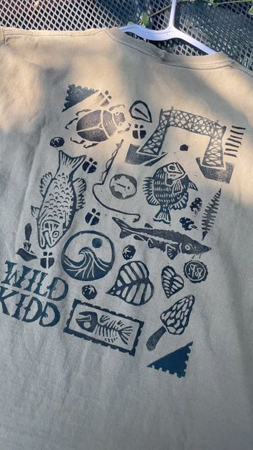 Wild Kidd Design | Anna Kidd on Instagram: "Which stamp is your favorite? 🐟  Got the block prints unpacked and had to whip a couple pieces together for the market tomorrow (cross your fingers for no rain :)  Block print collages are a personal favorite and I love the endless combinations that can come out of it while keeping cost lower than a hand sewn piece AND turning trash into treasure  Truly a win win win for me, you and mama earth 🌍 ❤️  Any stamp recommendations?  #trashtotreasure #upcycling #upcycledfashion #blockprinting #natureartist #minnesotaartist #wearableart" Block Printing Clothes, Block Print T Shirt, Screen Printing Ideas, Block Print Shirt, Trash Into Treasure, Mama Earth, Cross Your Fingers, Earth Mama, Chair Ideas