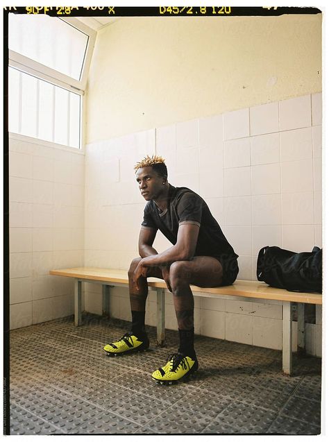 Black male footballer in changing room by Javier Díez for Stocksy United Football Changing Room, Changing Room Photoshoot, Locker Room Photoshoot, Football Locker Room, Football Photoshoot, Locker Room Sports, Lions Football, Red Lion, Man Sitting