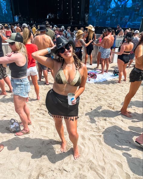 Girl wearing a black cowboy hat, black sunglasses, black bikini and black knit skirt posing in front of the main stage at Tortuga music festival on the beach in Fort Lauderdale Tortuga Outfits, Trendy Brown Top For Festival, Tortuga Music Festival Outfit, Tortuga Outfit Music Festivals, Trendy Pre-shrunk Tops For Music Festivals, Tortuga Festival Outfit, Music-themed Tops For Concerts And Music Festivals, Summer Music-themed Tops For Music Festival, Tortuga Music Festival