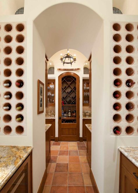 An elegant archway is flanked by built-in stone wine racks that hold the homeowners' collection. Warm wood cabinets paired with traditional countertops provide storage for glasses, decanters and other entertaining needs. Terracotta tile grounds the space, while a rustic chandelier adds an Old World note. Hacienda Architecture, Wine Barrel Sink, Mediterranean Wine, Spanish Homes, Wine Rooms, Spanish Mediterranean, Home Wine Cellars, Basement Inspiration, Big Room